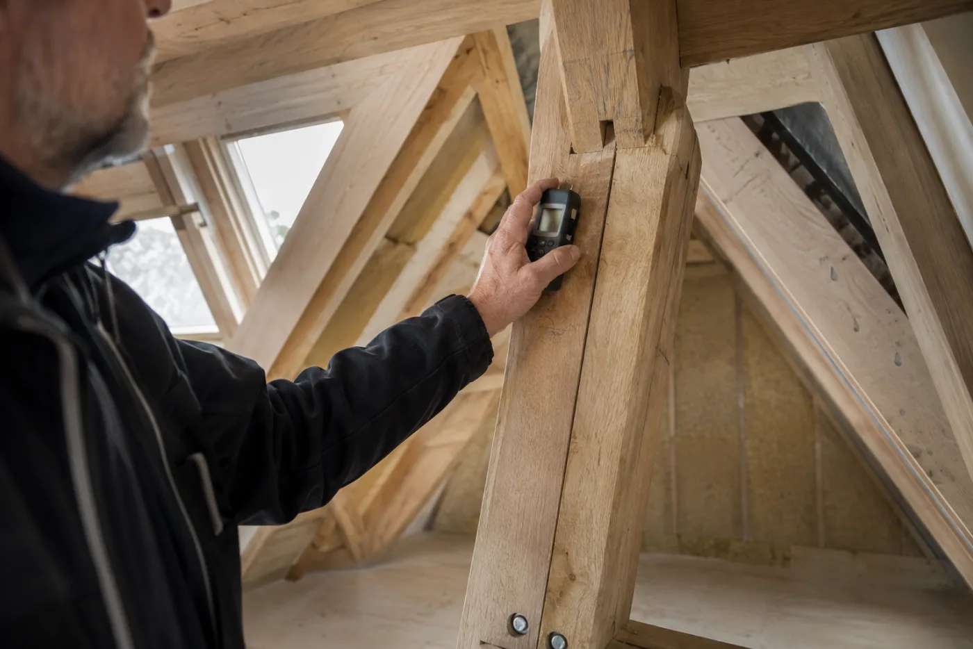 Vakman meet het vochtgehalte van een houten dakconstructie